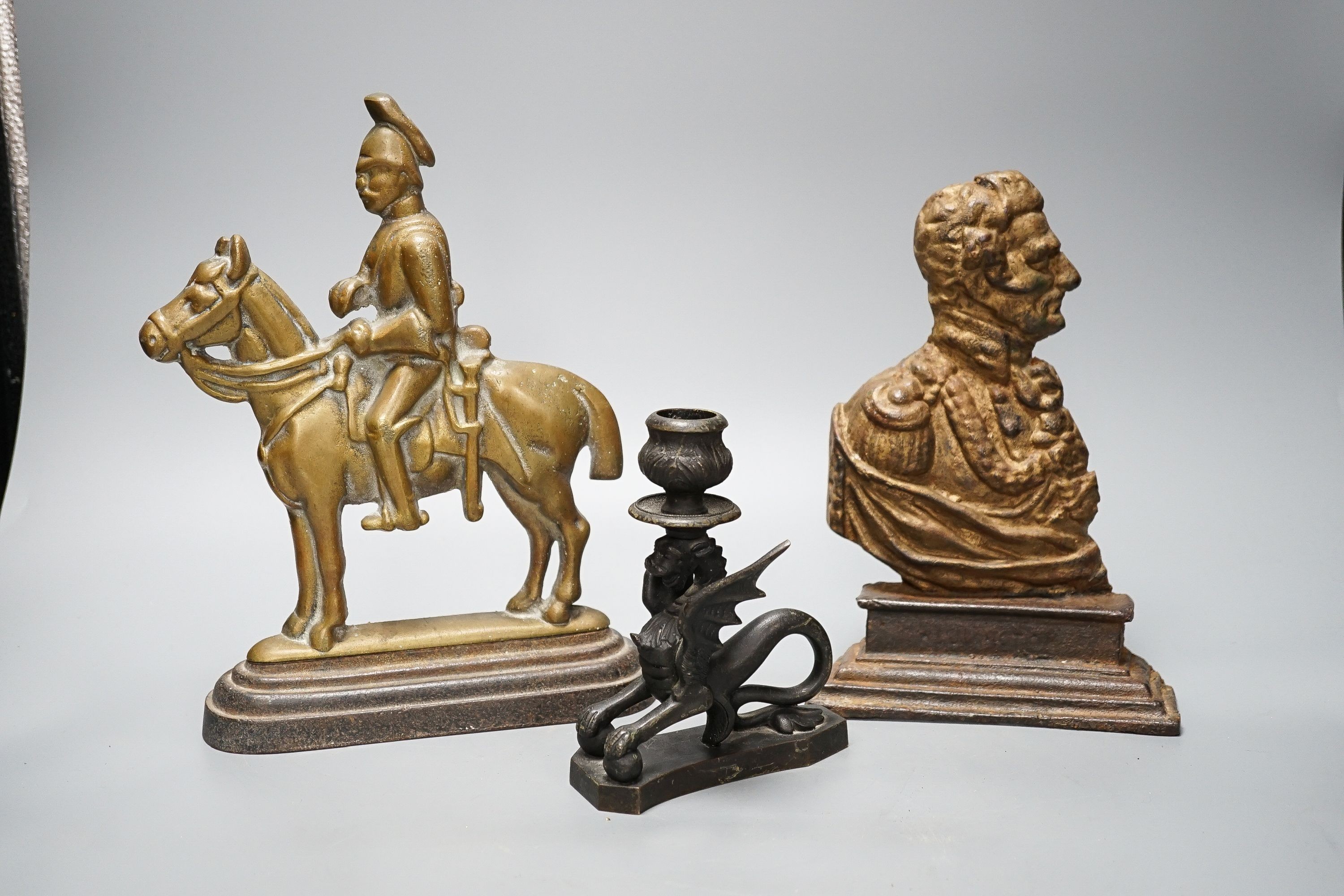 Two brass and cast iron military doorstops and a brass chamberstick 26cm